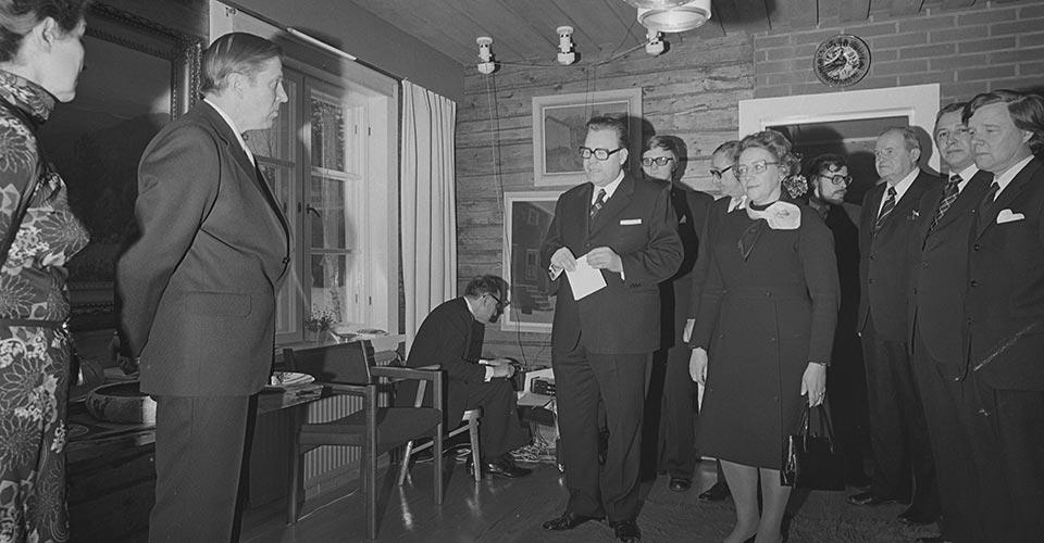 Mustavalkoinen valokuva, jossa Opetusministeri Marjatta Väänänen ja ministeriön virkamiehet onnittelemassa Johannes Virolaista tämän 60-vuotispäivänä.
