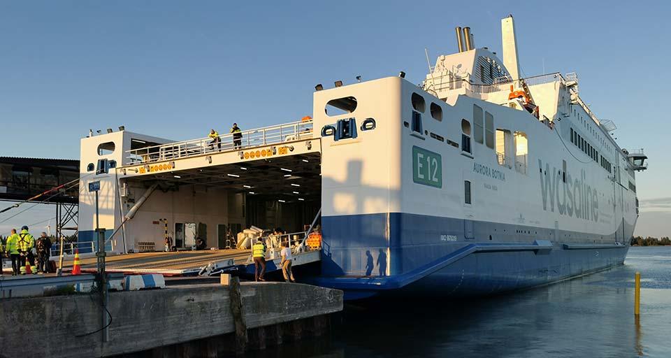 Kuva Wasaline-laivan takaosasta, jossa luukku ruumaan on auki ja laivan työntekijät ovat menossa sieltä sisään.