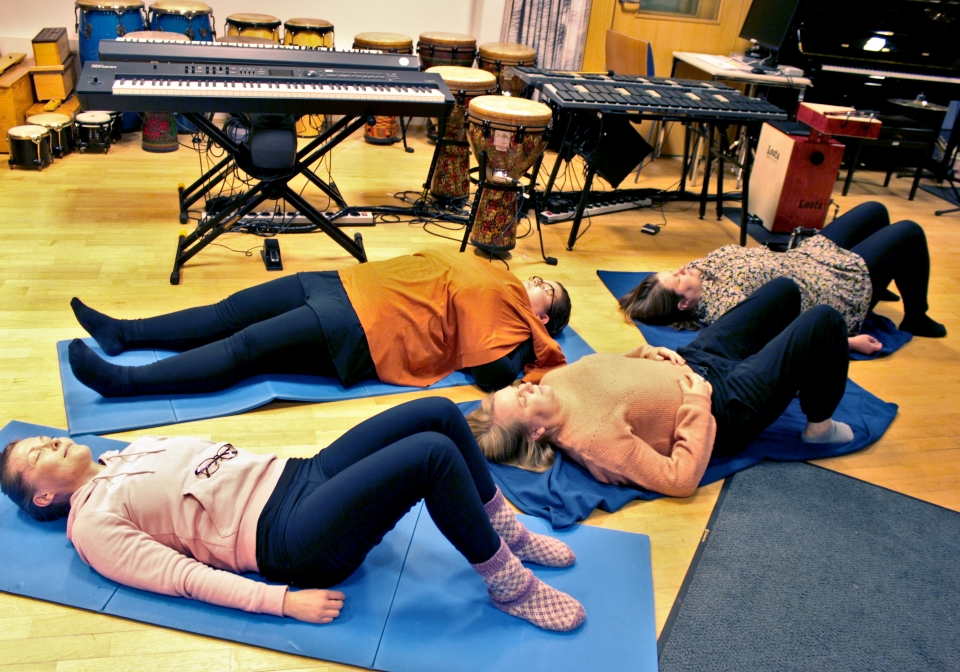 Music therapy students are lying on the floor and practising resonance frequency breathing.
