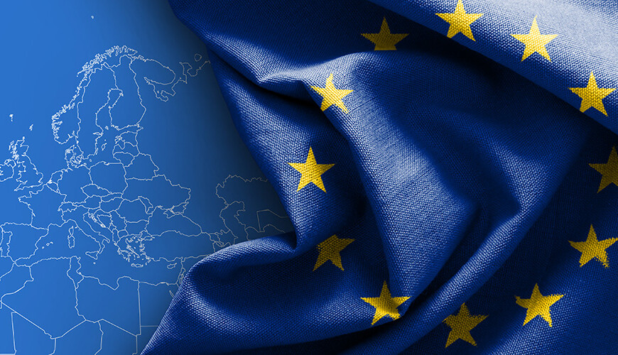 Vasemmalla puolella on siniselle taustalle piirretty Euroopan maiden rajat valkoisella viivalla, oikealla puolella on laskoksilla oleva Euroopan unionin lippu.