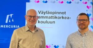 Kaksi henkilöä seisoo ilmoituksen edessä, jossa lukee: Väyläopinnot ammattikorkeakouluun.